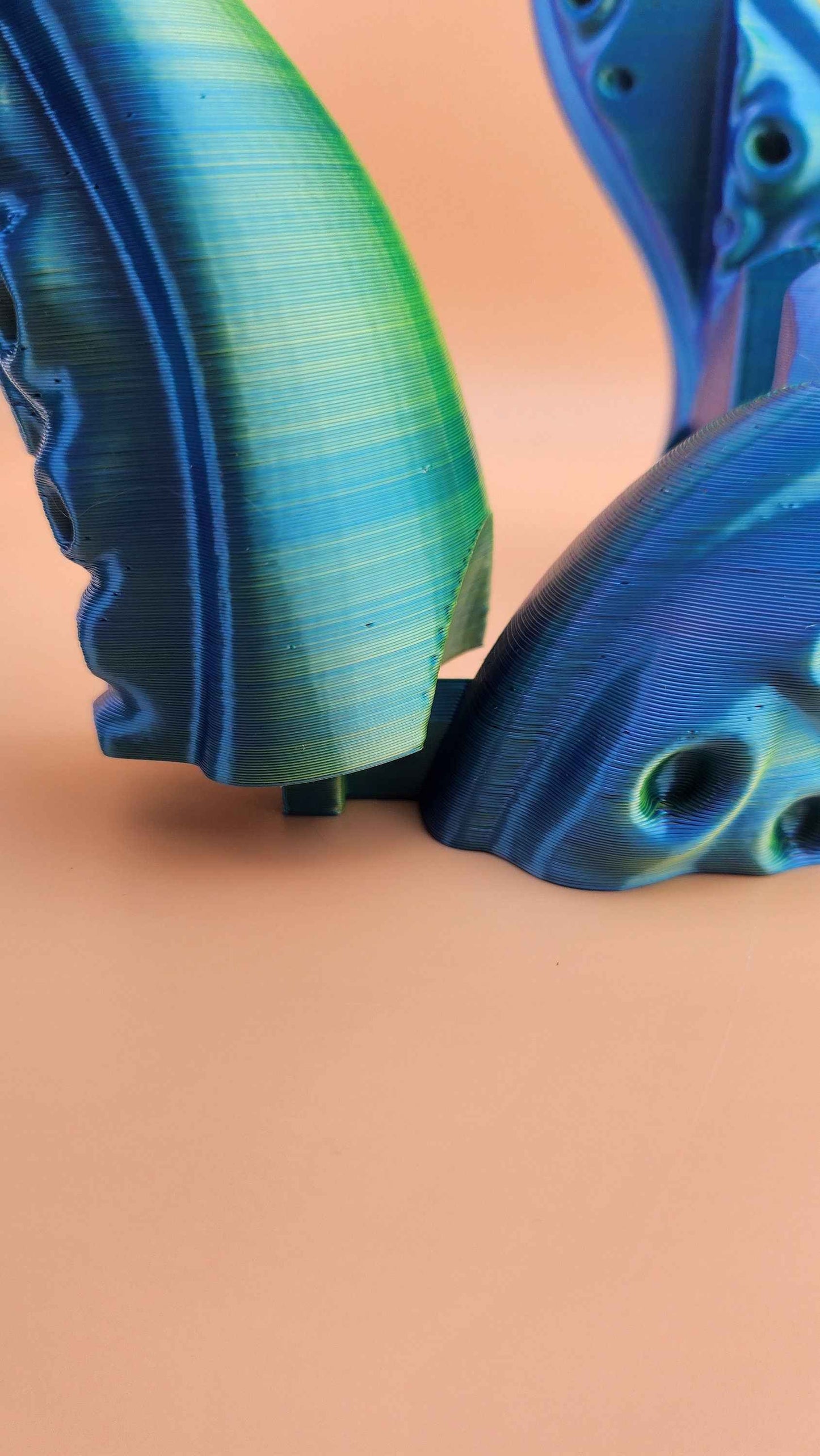 Extreme close-up of the stand's base, highlighting the glossy transition from lime green to deep blue.