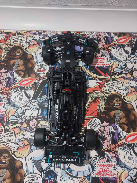 Straight-on view of the large black Lego F1 model mounted vertically against the vivid Star Wars comic wallpaper.