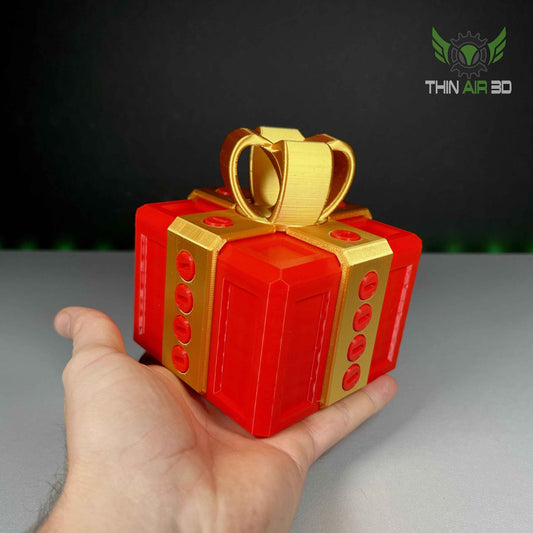 Side profile of the elaborate red and gold gift box puzzle, held securely in an adult's hand for scale comparison.