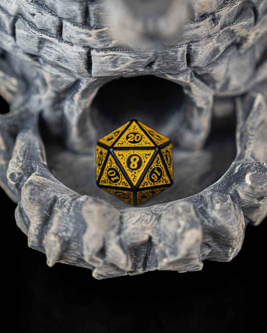 Extreme close-up of the textured grey stone dragon's mouth holding a yellow and black twenty-sided die (D20).