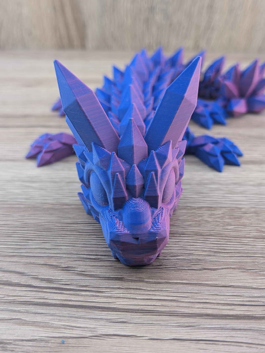 Close up, head-on view of the articulated crystal dragon's face, showing blue and magenta duotone material.