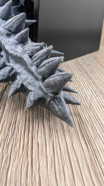 Close-up showing the texture details of the sharp, conical spikes at the tip of the dark grey dragon tail.