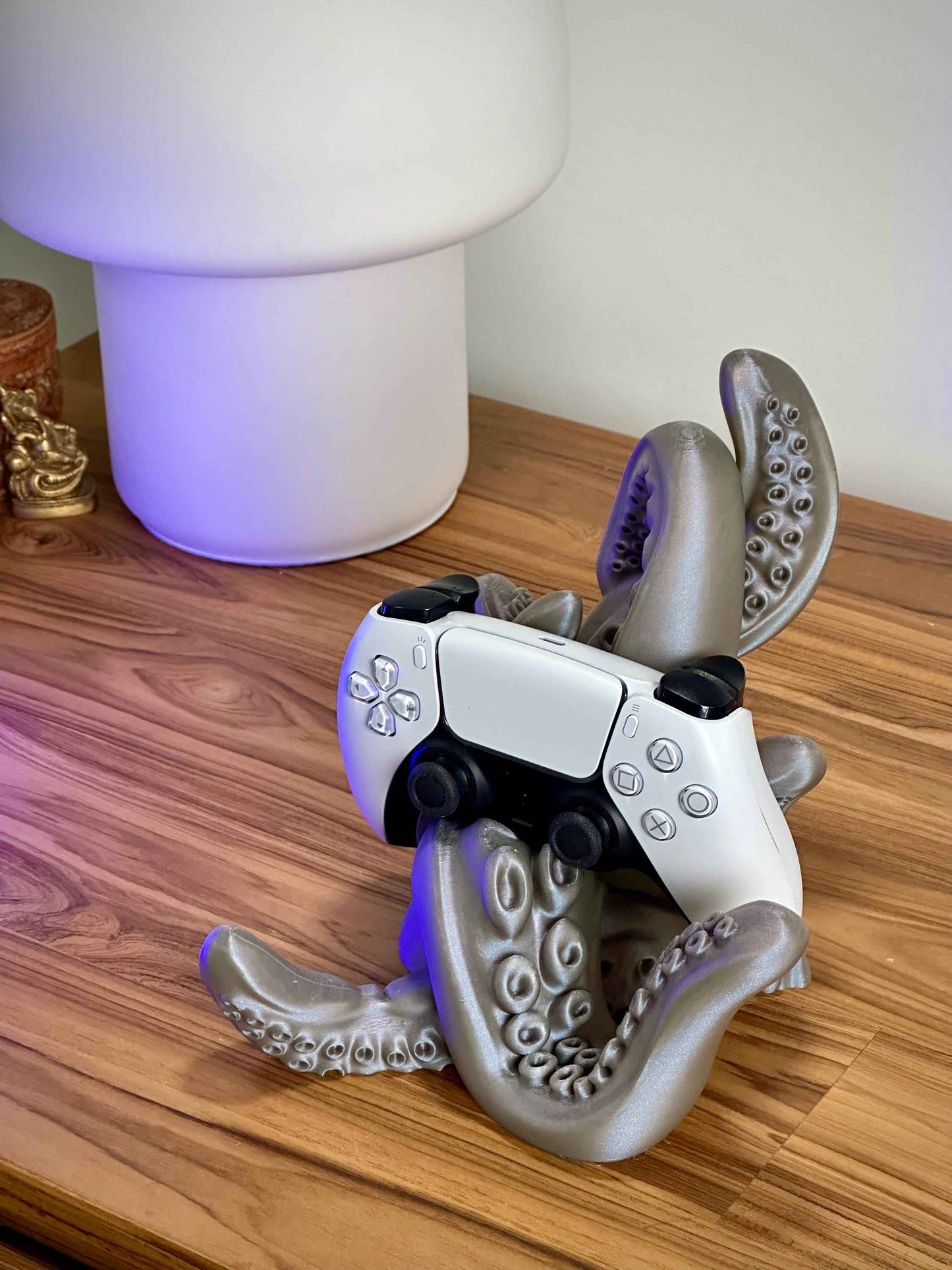Grey silver tentacle controller holder holding a white PS5 controller on a wooden desk.