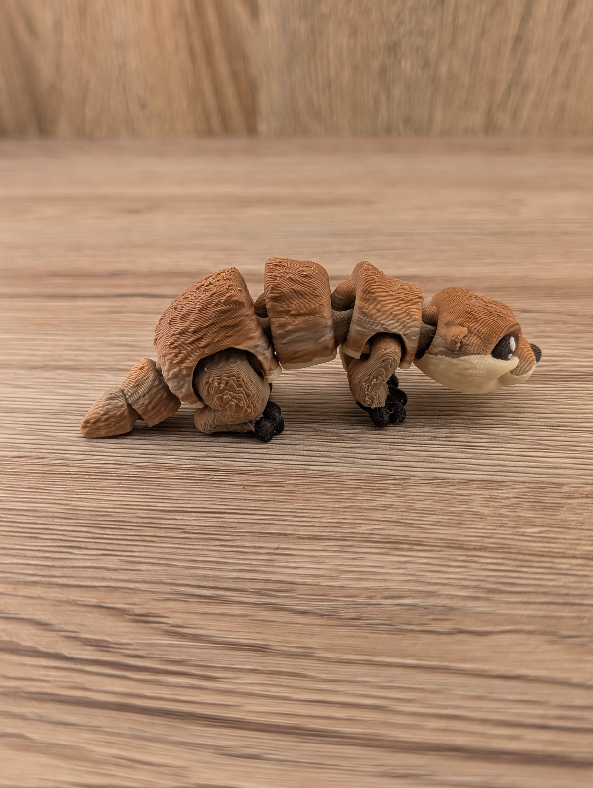 Side view of the textured brown segmented figurine. The flexible body joints and multi-part tapering tail are clearly visible.