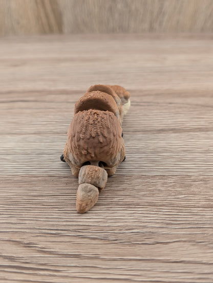 Rear view of the brown segmented toy animal. Detailed layered texture visible across the body and rounded, flexible tail.