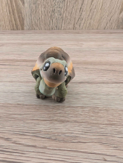 Front three-quarter view of the mini turtle fidget toy on a wooden surface