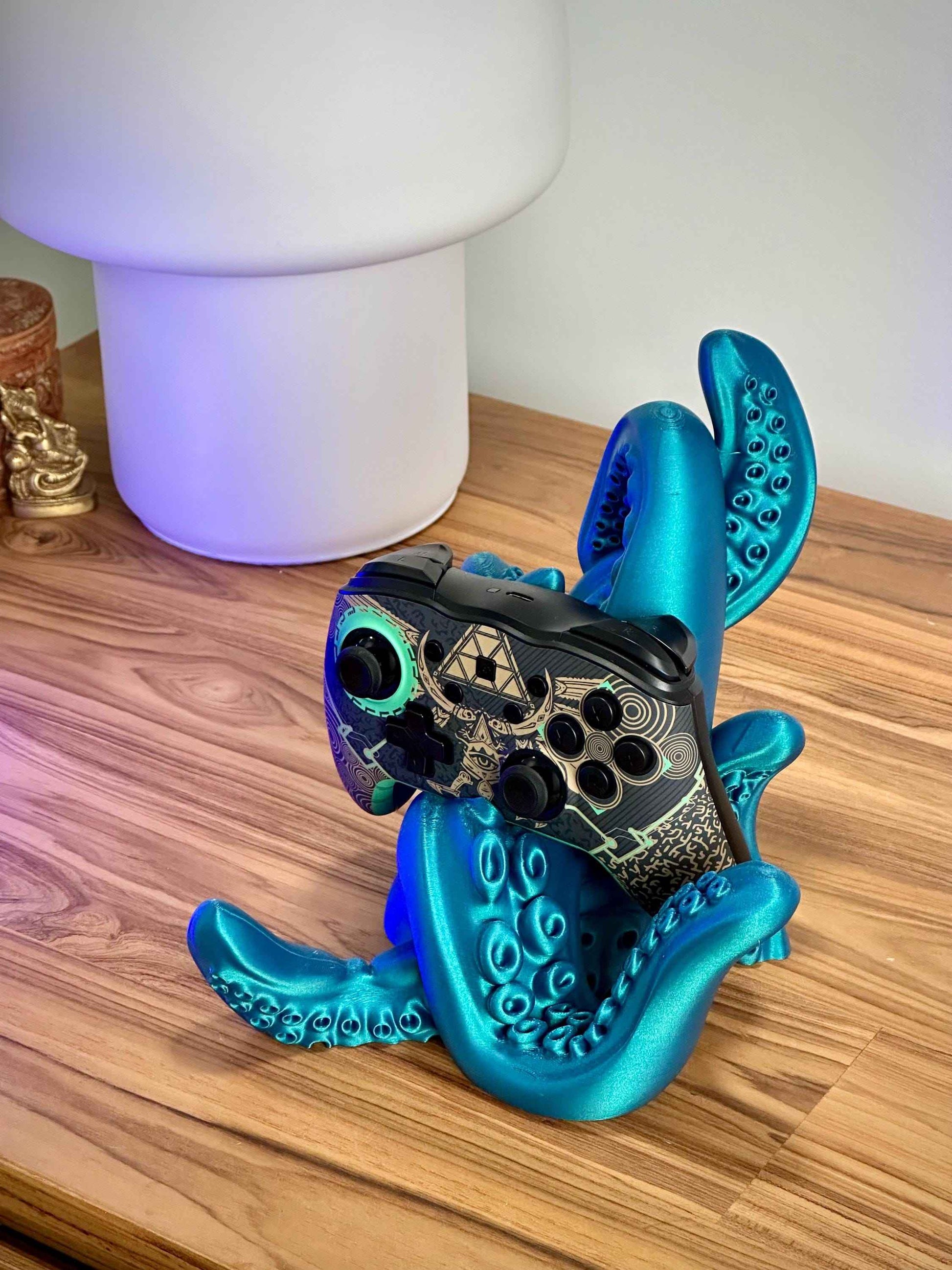 Shiny Blue tentacle controller holder holding a Zelda Switch Pro controller on a wooden desk.