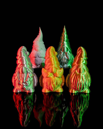 Five gnomes illuminated by red and green light on a reflective black surface. Close group shot.