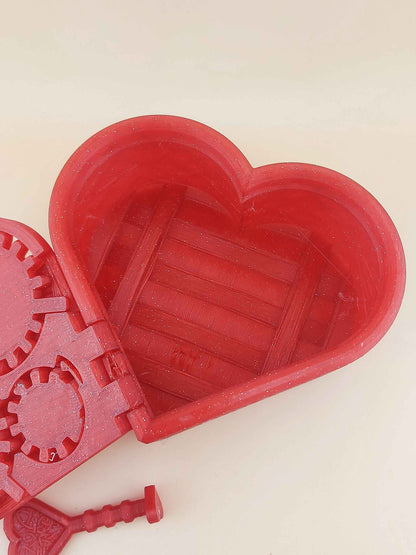 Close up view of the sparkly red heart lockbox opened, emphasising the empty interior and the hinged geared lid.