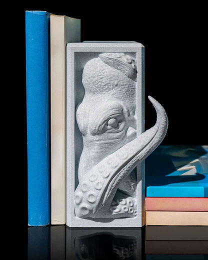 Light grey, stone-textured kraken bookend holding two stacks of colourful books vertically.