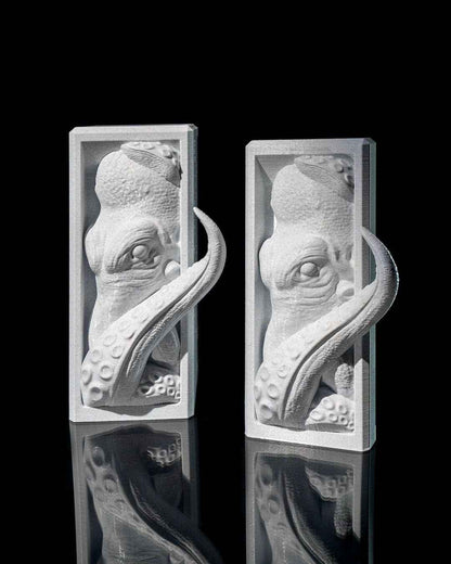 Twin silver kraken bookends in rectangular relief panels, highly textured detail on the head and tentacles.