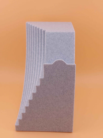 Speckled grey stand side profile showing a stepped, angular design against a solid peach background.
