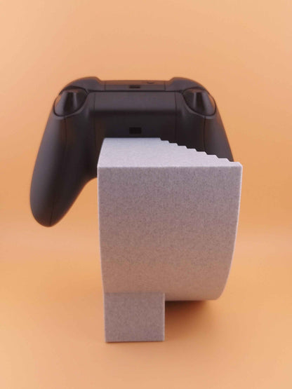 Back view of the black controller resting high above the simple, speckled grey geometric stand.