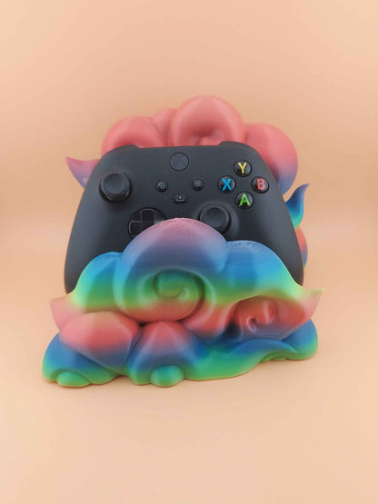 Centred front view of a black controller held securely by smooth, layered plastic shapes in strong pink, blue, and green gradients.