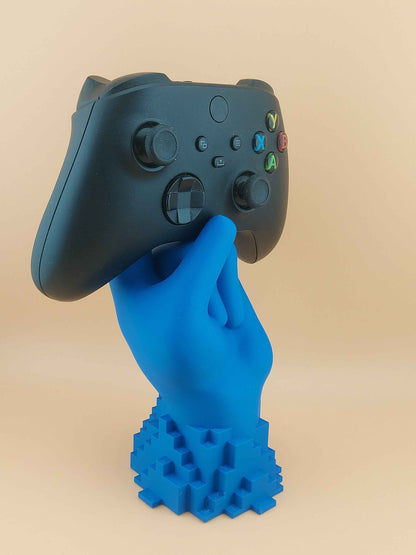 Tilted front view of a black Xbox controller held by a matte blue hand stand, showing the coloured buttons.