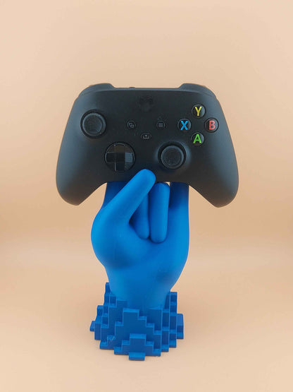 Frontal view of a black Xbox controller resting in a bright matte blue hand holder with a pixelated base.