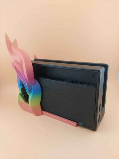 Rear view of the black Nintendo dock, showing the smooth, curved pink and blue rainbow feathers wrapping the side.