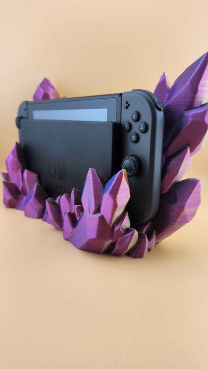 Low angle side view of the colour-shifting purple crystal stand framing the Nintendo Switch's right joystick.