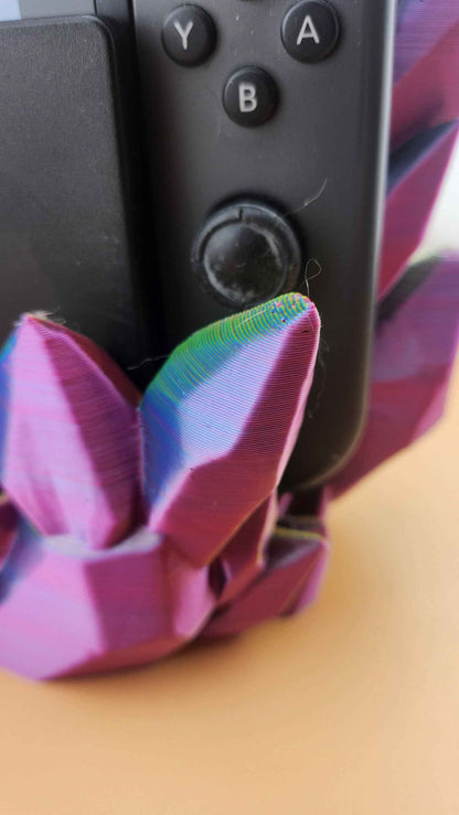 Macro close up of a sharp, purple crystal tip cycling to rainbow colours against the black joystick grip.