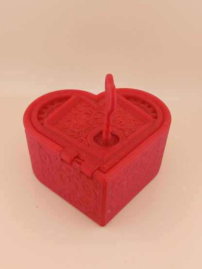 Closed sparkly red heart box shown with the small, heart-topped key inserted vertically into the central keyhole.