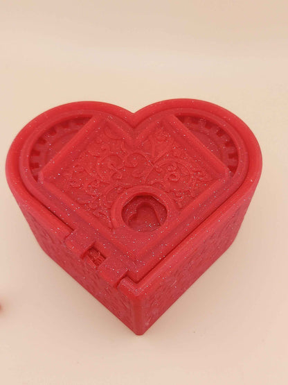 Closed sparkly red heart puzzle box, centred. The lid features decorative filigree patterns around the keyhole.