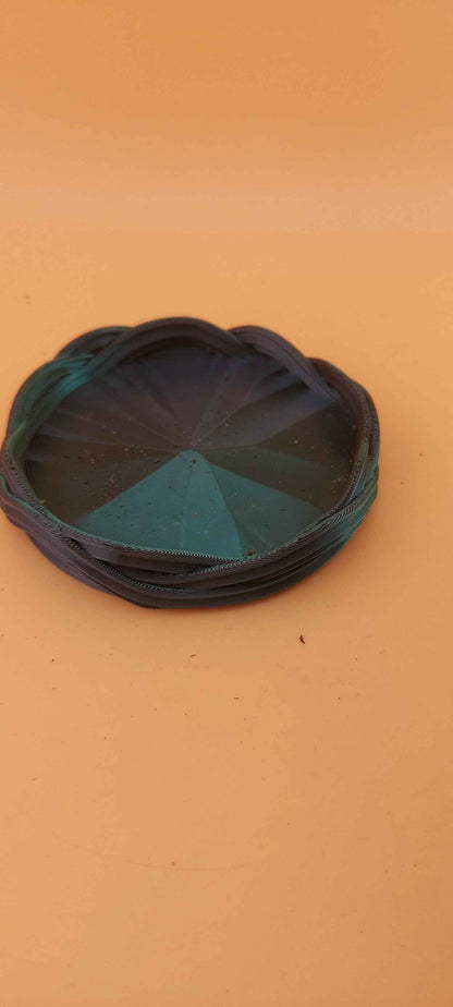 Detached circular planter base with a woven teal rim and a faceted, dark blue conical centre. Close-up view.
