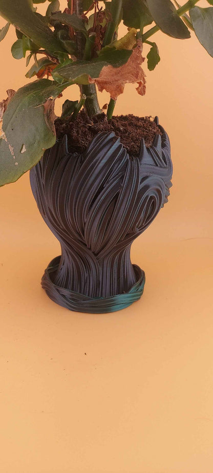 Back profile of the planter showing dramatic, dark teal, wavy sculptural textures flowing down to the base.