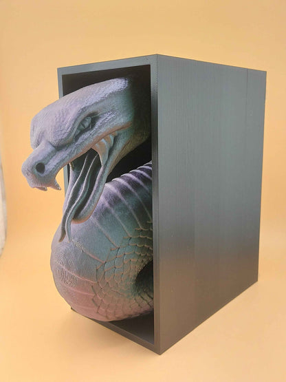 Three-quarter rear perspective showing the snake coiled deeply inside the black bookend, head turned slightly outward.