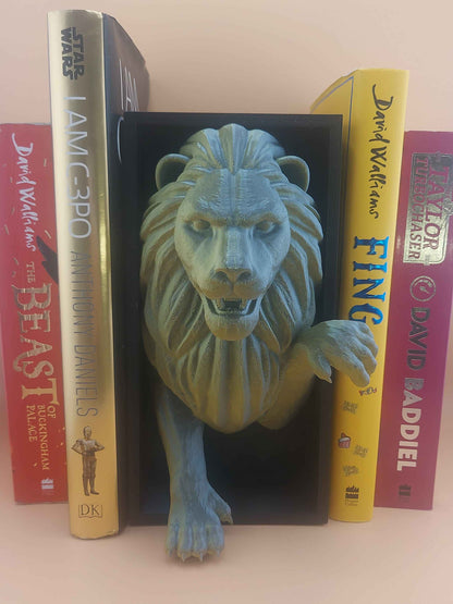 Matte green-gold roaring lion bookend emerging from a black box, holding up four colourful books.