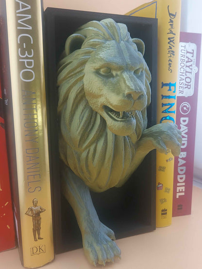 Close up of the fierce green lion bookend's face and gripping paw nestled between books.