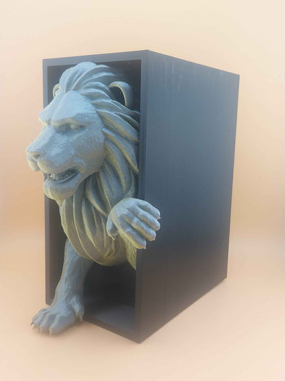 Left side profile of the matte grey-green lion emerging mid-stride from a solid black box on a beige surface.