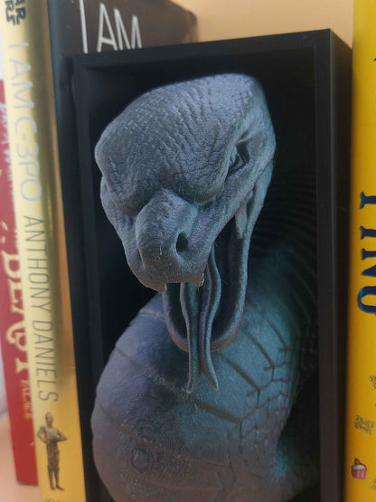 Close-up, slight angle on the matte grey snake's textured head, showing the curled tongue inside the black frame.