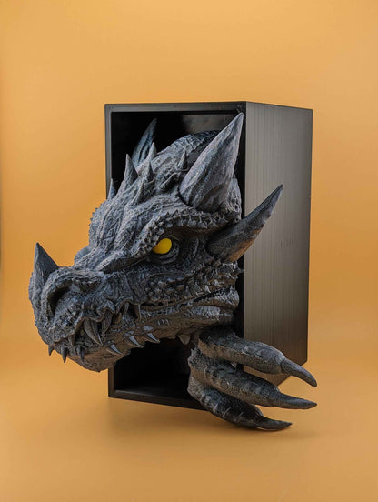 Dark charcoal dragon head and claws bursting from a black frame. The rough, scaled skin features bright yellow eyes.