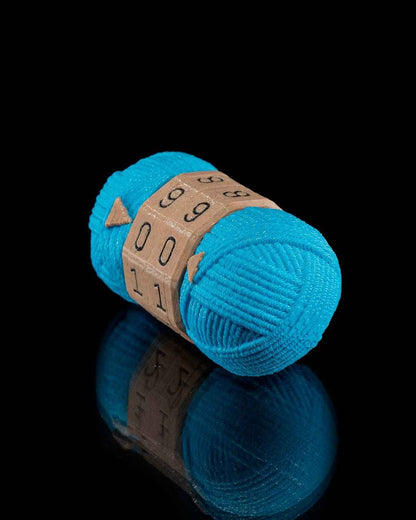 Dynamic side profile view of the bright teal yarn fidget counter. The cardboard-look dials show the numbers 99, 00, 11.