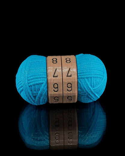 Front view of the teal yarn counter fidget with reflective sheen below. The brown dials are currently set to 88, 77, 66.