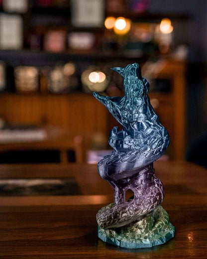 Side profile of a winding, iridescent dice tower sculpture in shimmering teal, violet, and olive hues.