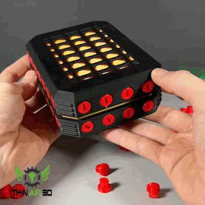 Two hands hold the black modular box. Grille top reveals a glowing yellow interior lining, highlighting red accents.