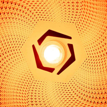 Bright light bulb viewed straight through the hexagonal fixture hole, surrounded by the highly saturated, illuminated orange mesh.