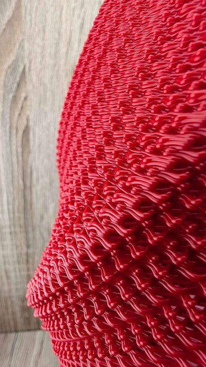 Extreme close-up side view of the glossy, vibrant red texture, composed of tight, overlapping rows of raised, wavy forms.