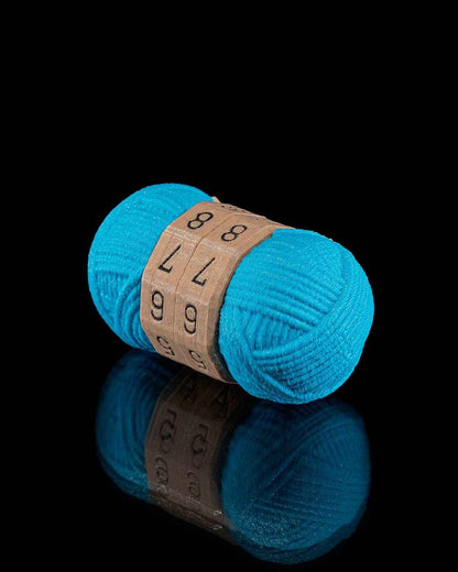 Slightly angled front view of the teal yarn counter fidget on a black surface. The central brown dials are set to 88, 77, 66.