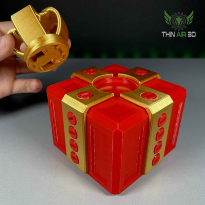 Close up shot showing the golden bow element being lifted from the red gift box puzzle, exposing the keyhole mechanism on the lid.