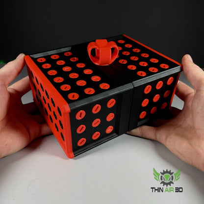 Black and matte red snap-together modular box stabilised by two hands, highlighting the side and top accent features.