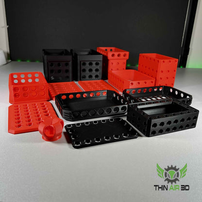 A large collection of disassembled modular container parts: black bases, red trays, and lids spread out on a white surface.