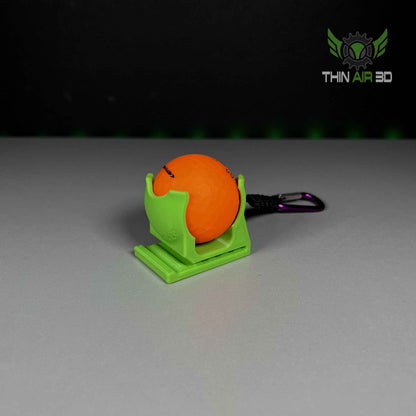 Single orange golf ball in a bright lime green caddy with a purple carabiner attachment.