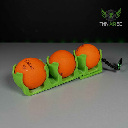 Three orange golf balls lined up perfectly inside a matte lime green, three-pocket ball carrier.