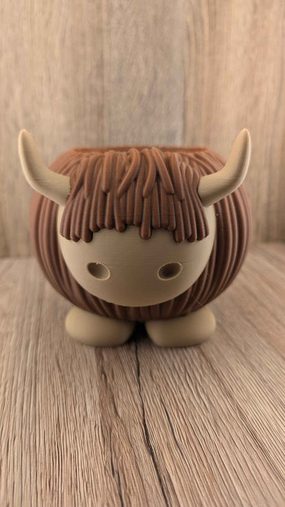Front close-up of the charming Highland Cow planter, showing the brown hair fringe and tan face with eye holes.