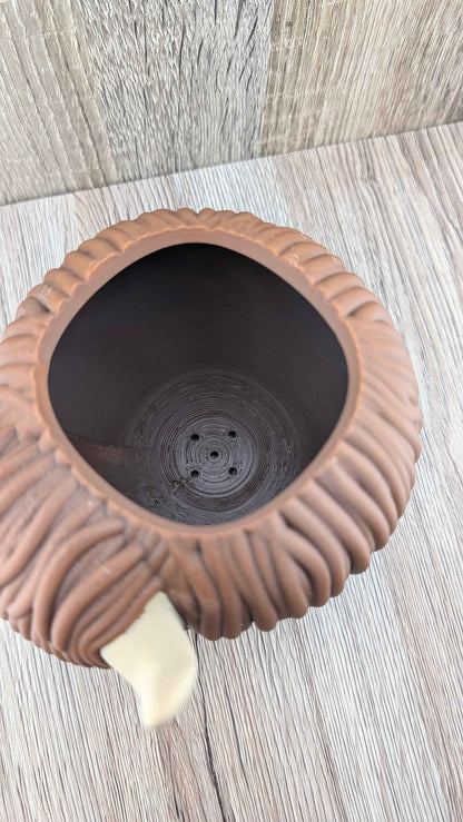 Overhead shot looking into the deep, dark brown cavity of the shaggy cow planter, showing the central drainage holes.