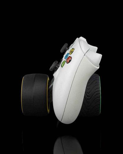 Side profile view of the white Xbox controller mounted on a yellow slick tyre and a green treaded tyre.