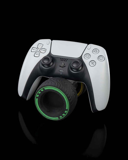Angled front view of a white and black PS5 controller balanced on a treaded tyre with a neon green rim.