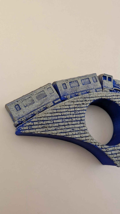 Close up showing the highly textured faux-brick bridge and golden train cars over a bright blue base.